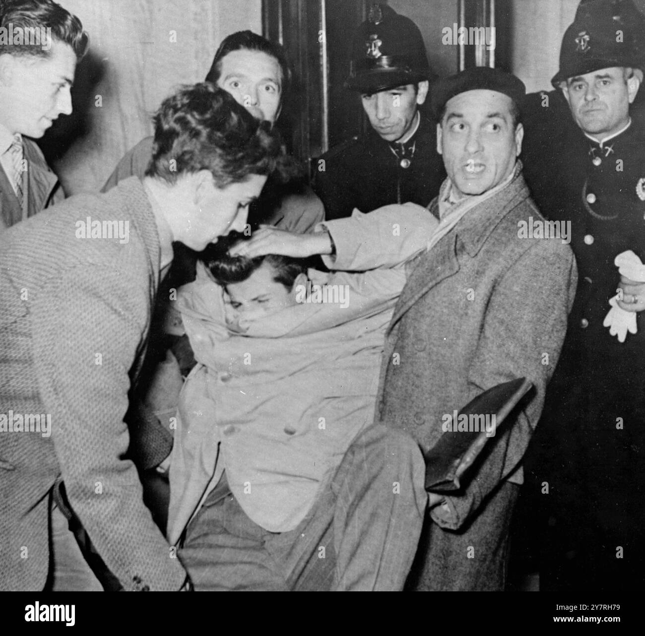 Immagine dalla radio. Le rivolte di Trieste si sono diffuse. 7.11.53. Ieri a Trieste sono scoppiate nuove rivolte e altre quattro persone sono state uccise. Una folla, stimata a 75.000, si precipitò per le strade urlando slogan e distruggendo edifici. Le granate sono state lanciate contro la polizia e sono iniziati gli incendi. Le truppe britanniche e americane sorvegliano gli edifici pubblici e le installazioni militari, ma finora non si sono scontrate con i manifestanti. La foto della I.N.P. mostra la guardia della polizia mentre un sommossa ferito viene portato via per essere curato durante le rivolte di ieri a Trieste. 142/PJ/72423 foto di notizie internazionali. Immagine dalla radio. Costo: Dail Foto Stock