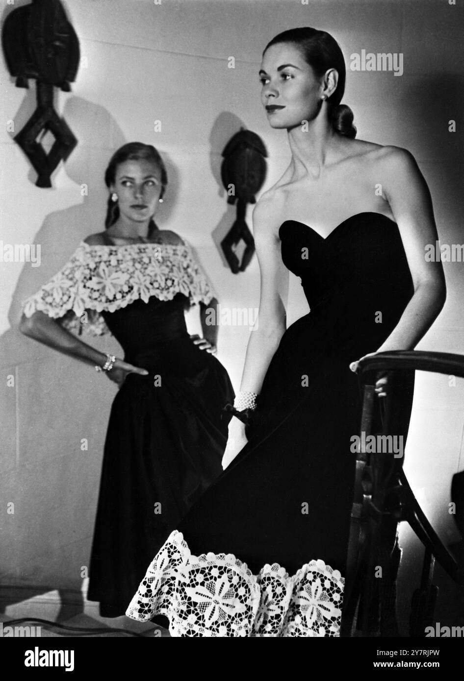 IL BALLET SKIRTLucien Lelong ha introdotto una nuova gonna da sera lunga stinco, chiamata Ballet Skirt. Spettacoli fotografici : due dei nuovi abiti. A sinistra, un abito da sera senza spalline in taffeta nero con gonna full e una linea imbottita all'anca. A destra, un abito senza spalline in velluto nero con corpetto aderente e una gonna svasata con un bordo in pizzo di 25 cm. Foto Stock