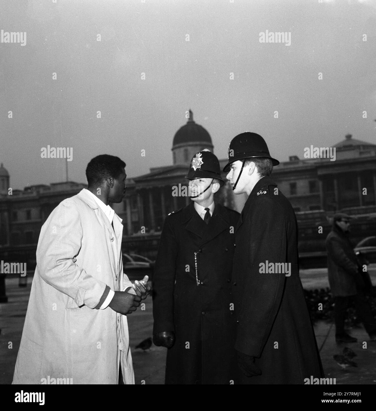 HEAVYWEIGHT HILTON A LONDONLondon, Inghilterra, Regno Unito : nella foto con due poliziotti a Trafalgar Square di Londra questa mattina c'è il pugile dei pesi massimi USA Hubert Hilton, qui per combattere l'inglese Henry Cooper ad Olympia, il 25 gennaio. 20 gennaio 1966 Foto Stock