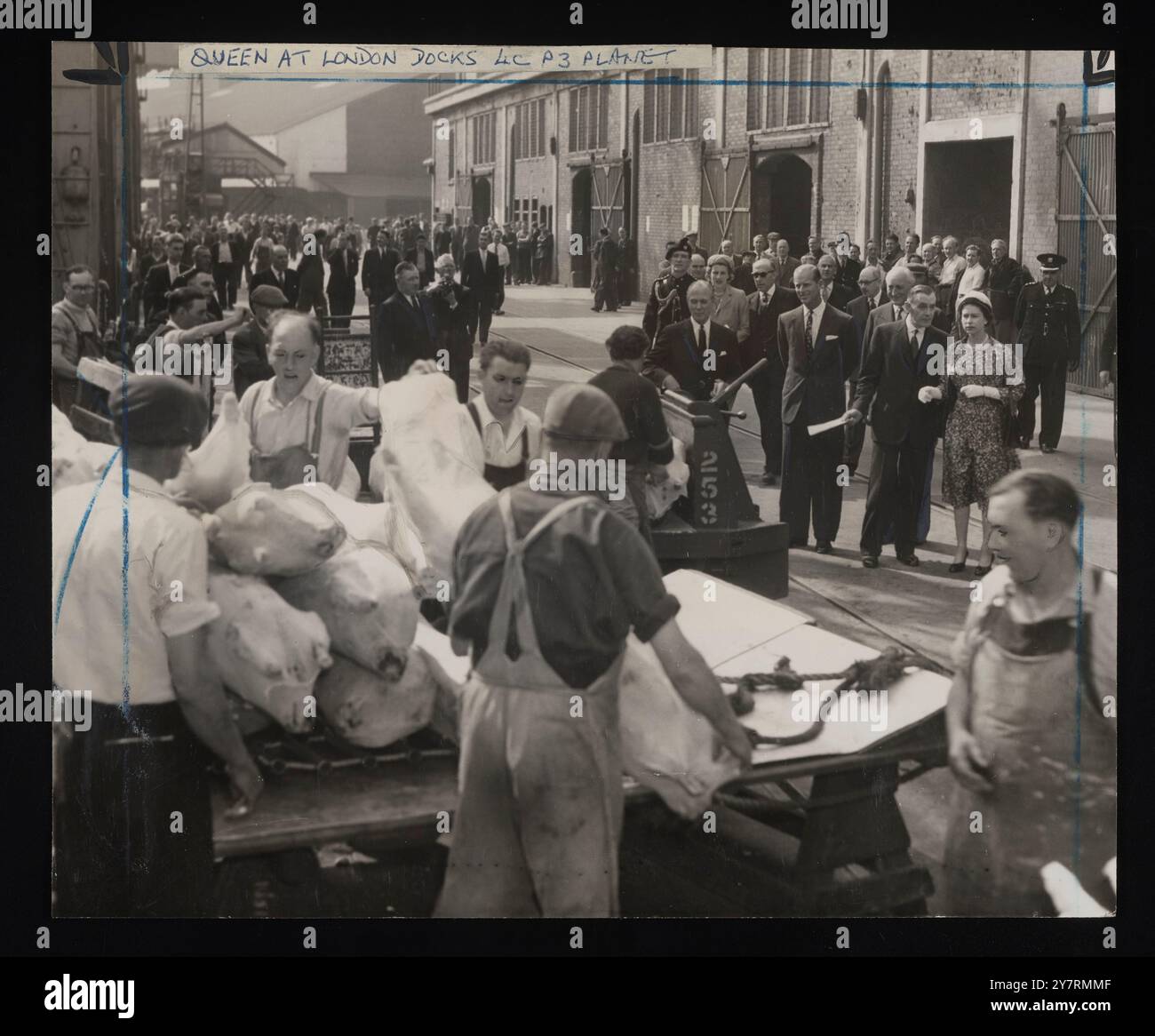 Porto l'unica bevanda. Quando la visita reale ai moli di Londra fu inserita nel libro di fidanzamento della Regina in un giorno crudo e umido lo scorso ottobre, nessuno sognava che la temperatura di metà maggio sarebbe stata negli anni '80 Ma era così ieri, e tutto quello che la regina e il principe Filippo dovevano bere era un bicchiere di porto. L'hanno capito quando hanno guardato intorno a una cassaforte per vedere i vini in legame. Altrove, era tutto come al solito. Questi lavoratori della carne erano tra i fortunati a Docklands ieri. Ogni tanto si respiravano nel freezer. 13 maggio 1959. Planet News. Foto Stock