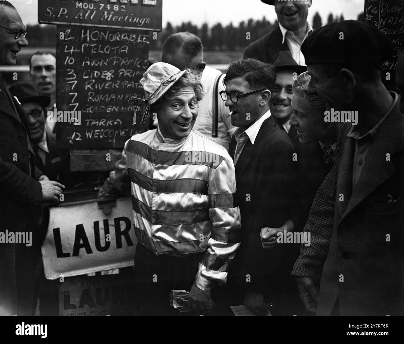 Harpo dirige un libro in un giorno alle gare Harpo Marx , famoso comico americano stupido al momento presente al London Palladium, ha partecipato alle gare di Alexandra Park. Ha fatto una bella sensazione con il suo vestito da corsa. Ha sostenuto un vincitore nella prima gara, "Dombey" Photo Shows: Harpo interpreta il bookmaker, completo di borsa e banconote che si attaccano dal cappello all'Alexandra Park oggi 2 luglio 1949 Foto Stock