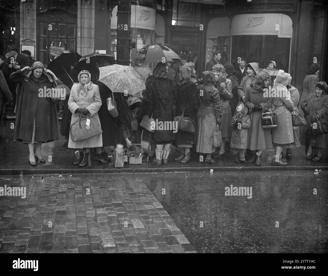 ASPETTANO SOTTO LA PIOGGIA LA PROCESSIONE FUNEBRE DEL RE 11-2-52 SPETTACOLI FOTOGRAFICI:- ombrelli e mackintosh erano molto utilizzati da persone che hanno tracciato il percorso per la processione funebre del re attraverso Londra fino a Westminster Hall oggi. Ecco una scena fuori dalla stazione di Kings Cross, dove la bara stava arrivando dalla stazione di Wolferton. Folla 11 febbraio 1952 Foto Stock