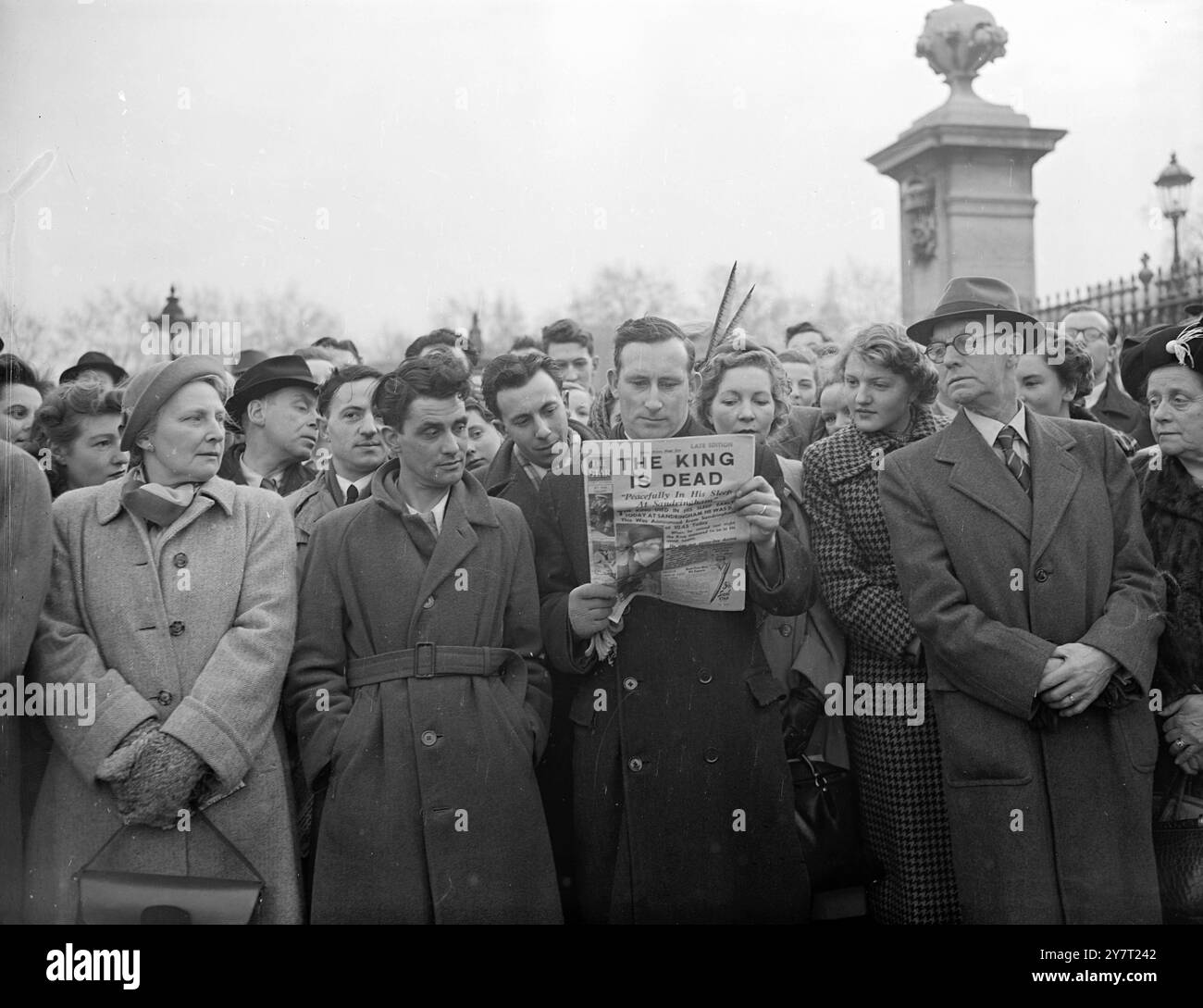 MENTRE LEGGONO NOTIZIE DELLA MORTE DEL RE FOLLE ASPETTANO FUORI PALAZZO 6-2-52 folle si riuniscono fuori Buckingham Palace, Londra, oggi dopo la notizia della morte del re. Sua Maesta' e' morta pacificamente nel sonno a Sandringham, nel Norfolk. SPETTACOLI FOTOGRAFICI:- la folla fuori dal Palazzo stava leggendo i titoli delle ultime edizioni di carta serali che annunciavano la morte del re. Foto Stock