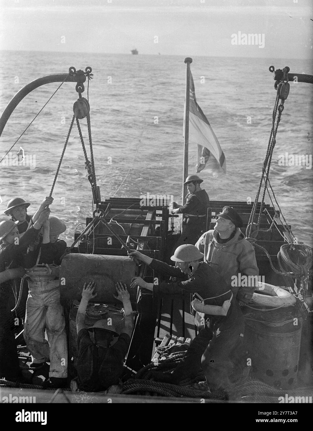 CONVOGLIO INVERNALE queste foto sono state scattate a bordo di una nave di scorta che ha accompagnato un convoglio che portava cibo dal mondo esterno e rifornimenti da porto a porto attraverso i mari invernali resi pericolosi dalle mine e dai sottomarini, i cieli in testa una costante minaccia da parte degli aerei da guerra tedeschi. Il tempo era brutto. Lo spray si è bloccato sui vestiti e sui volti dei pistoleri e degli uomini che stavano a guardare. I mari pesanti battono contro queste piccole navi. Hanno portato il loro carico. La foto mostra: Una carica di profondità caricata con cautela a poppa. 23 dicembre 1940 Foto Stock