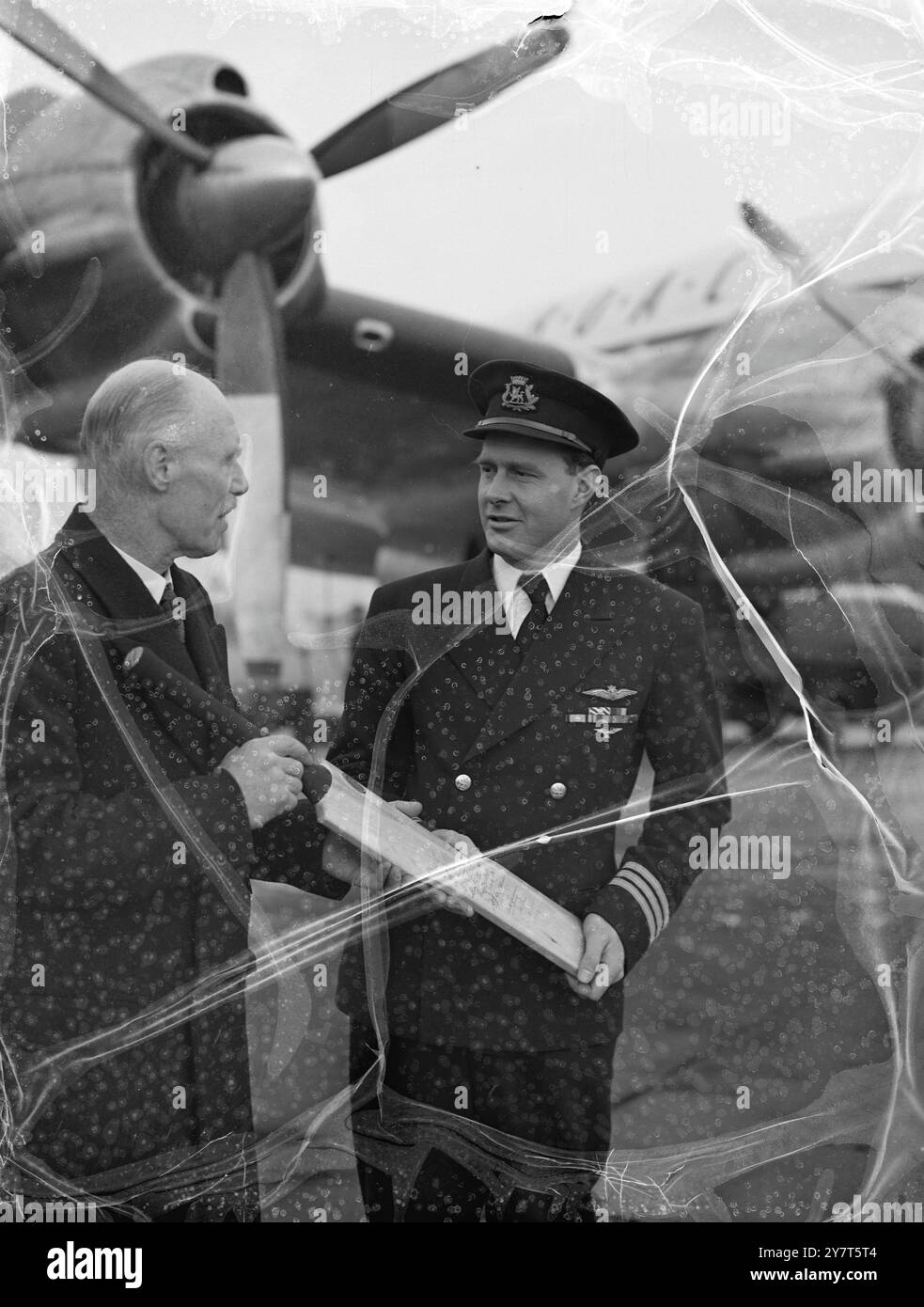 BAT INIZIA Un LUNGO VIAGGIO Cricket bat con un lungo viaggio e una missione da eseguire alla fine viene consegnato al Capitano G.M. ALLCOCK , D.F.C.( a destra) dal Capitano del gruppo S.J. BAILEY all'Aeroporto di Londra . Il capitano Allcock deve portare la mazza con il suo aereo B.O.A.C. in Giamaica. Il pipistrello è un dono della Royal Air Force Benevolent Fund , e deve essere venduto a Kingston per fornire attrezzature sportive ai giamaicani . Porta la firma dei giocatori di cricket delle Indie occidentali , che si sono recati a Britian la scorsa estate . Anche Sir Pelham Warner , famoso England Cricketer , firmò la mazza . Il Capitano del gruppo Bailey e' segreto Foto Stock