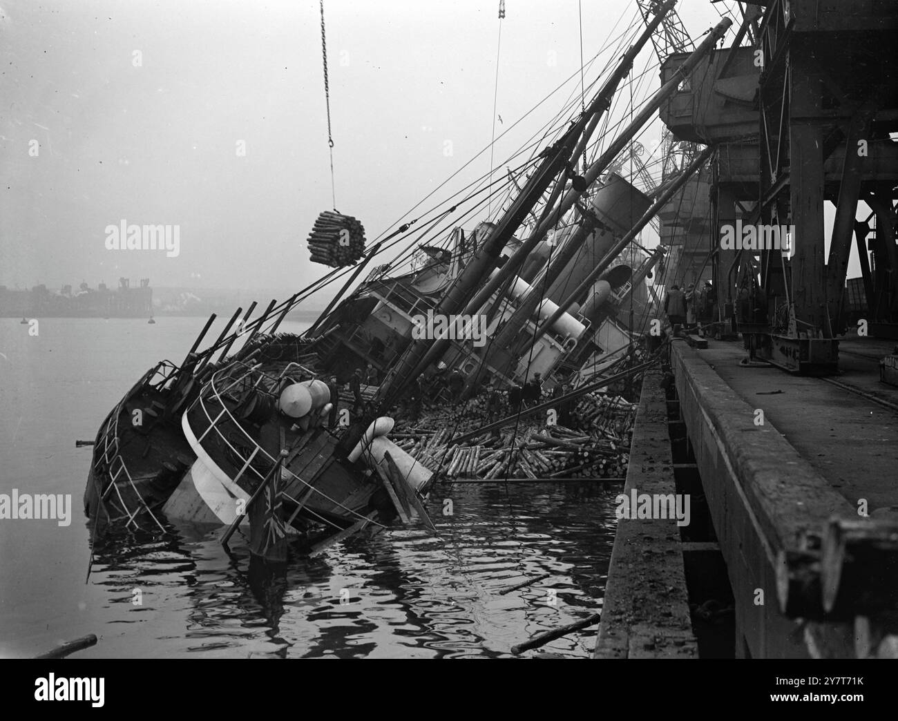 IL CARICO PRELEVATO DALLA NAVE CHE AFFONDÒ ALLA BANCHINA la sua sovrastruttura poggiata contro il molo nord-ovest di Tyne Dock, South Shields, il piroscafo di Belfast Dundrum Bay (1800 t) è sollevato dal suo carico di pozzi di poppa. Sono stati fatti dei tentativi per riparare la nave dopo che ha visto al molo. La baia di Dundrum aveva iniziato a scavalcare quando l'acqua era entrata nella sua stiva poche ore dopo che era arrivata con un carico di legname dalla Germania. 30 dicembre 1950 Foto Stock