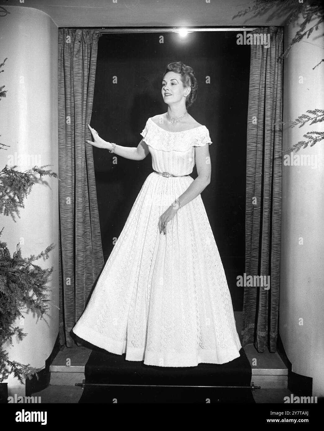 MEZZO MILIONE DI PUNTI PER LA BELLEZZA DEL manichino londinese SYLVIA SHELLEY modella questa creazione di una casalinga Sidcup ( Kent ) al Salone di moda primavera 1951 di International Wool Secretariat a Kensington , Londra . Abito da sera bianco crinolina, raffinato e leggero come il pizzo, ed è stato lavorato a mano dalla signora E.N. Reed. Contiene mezzo milione di punti e la signora Reed vi ha lavorato tra le faccende domestiche. La gonna completa è appesa su cerchi di crinolina e il corpetto ha uno scollo vittoriano a spalla. 1950 Foto Stock