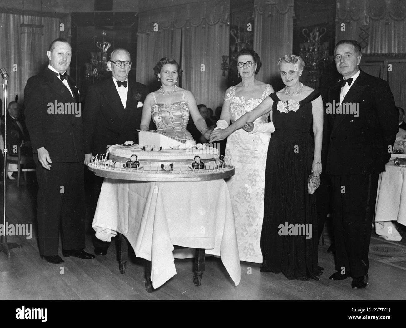 Una torta di quaranta chili è in vendita ai 400 ospiti che partecipano alla cena giubilare della Marconi Marine Company presso il Dorchester Hotel , Park Lane , W. da sinistra a destra , Sir George Nelson ( Presidente della compagnia ) ; MR H C Van de Velde ( Vice Direttore generale ) : donna Gioia Marconi ; Lady Nelson ; Sig ra H C Van de Velde ; e il Marchese Marconi. La torta disegnata in blu e bianco rappresenta le onde del mare. Aprile 1950 Foto Stock