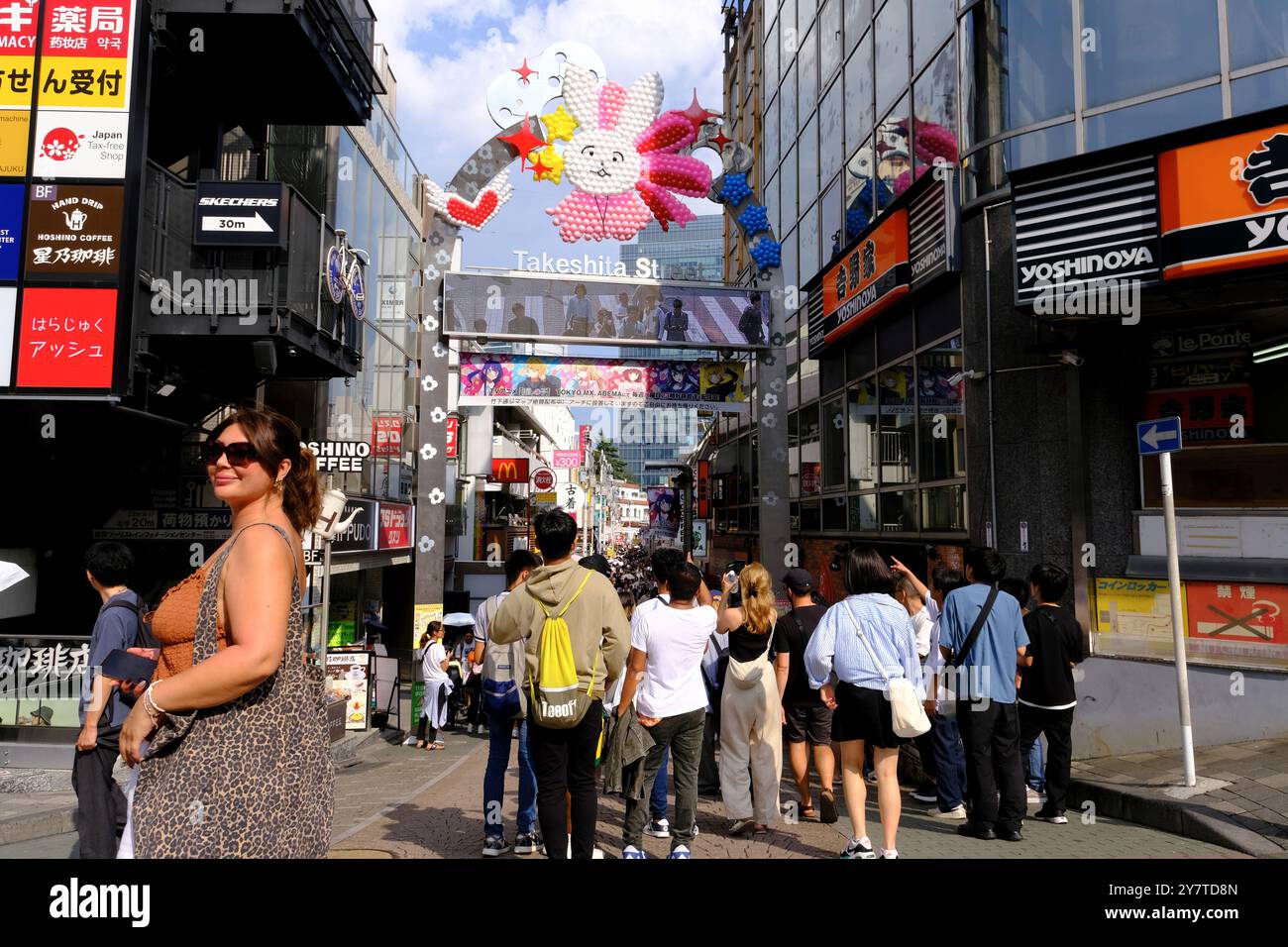 Una turista donna fa scattare la sua foto a Takeshita Street, un luogo popolare per adolescenti giapponesi e turisti ad Harajuku. Shibuya Ward. Tokyo, Giappone Foto Stock
