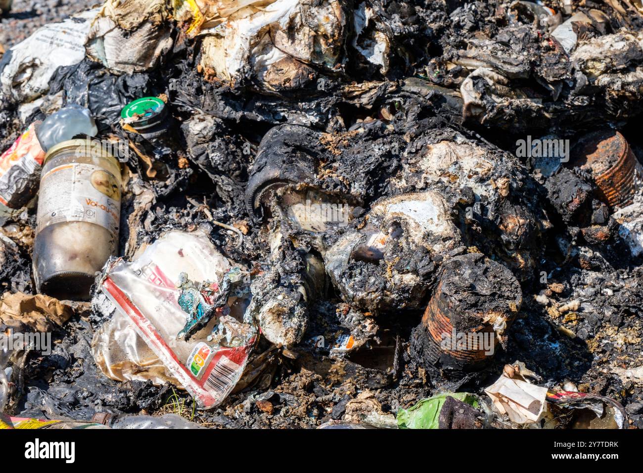 Vieux pneus de tracteur abandonnes au detour d'un bois et differentes canettes et bouteilles pourrissant et rouillant sur le sol. Vecchi pneumatici del trattore ab Foto Stock