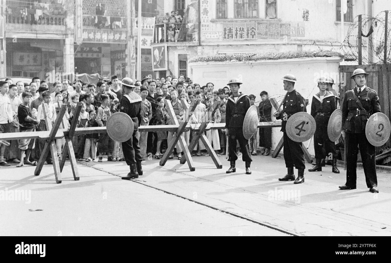 LA POLIZIA BARRICAVA LE STRADE DI HONG KONG CONTRO I RIVOLTOSI le barricate di filo spinato sono state gettate in fretta a Hong Kong dopo una battaglia campale tra polizia e rivoltosi in cui quasi 50 persone, alcune delle quali donne, sono rimaste ferite. La polizia ha gettato bombe a gas lacrimogeni in folle arrabbiate ammassate a Russell Street in simpatia con gli uomini della Tramway, che sono in sciopero per pagare di più dal 22 dicembre. I rivoltosi hanno bandito mazze, bottiglie e mattoni mentre si sono assaliti sul cordone della polizia. Si stima che, al culmine della sanguinosa battaglia, più di 10.000 affollarono l'area di Russell Street dove union e tram Foto Stock
