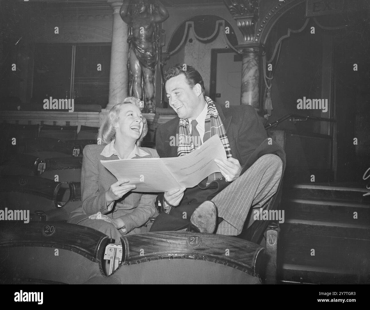 JOKE HIT THE MARK Carefree coppia in platea sono gioviali Bill Johnson, che ora suona in ' Annie Get Your Gun ', e Joy Nichols, star di ' Take IT From Here', che condivide uno scherzo al London Colisseum durante una prova per la Royal Variety. 4 novembre 1949 Foto Stock