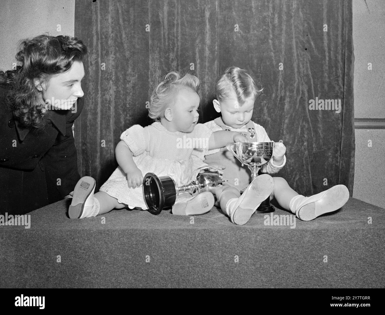 SOLO UN BAULE». A cosa serve una tazza se è vuota?" È un pensiero che sembra essersi venuto in mente a Christine Whitley (a sinistra), all'età di 12 mesi, poiché, avendo perso interesse per gli ampi spazi aperti del suo trofeo, si immerge una mano di ricerca in quella di John Menzies, di due anni e cinque mesi. Christine, di Ladbroke Grove, e John, di North Kensington, furono i principali vincitori del premio alla finale di un concorso per bambini di Kensington-and-District tenutosi nel cinema reale, Ladbroke Grove, Londra oggi. 26 finalisti, su 1.000 partecipanti, erano davanti ai giudici. 4 novembre 1949 Foto Stock