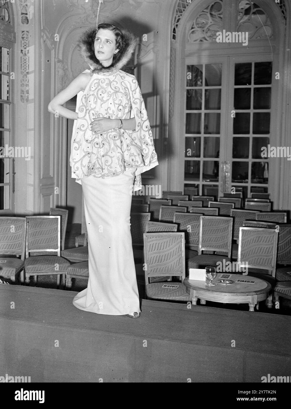 Più di una dozzina di paesi hanno inviato i loro migliori prodotti a Londra per la prima sfilata internazionale di tessuti e moda al Savoy Hotel di Londra. Organizzata dal Segretariato Internazionale della Lana, la mostra 'Lana Internazionale' è considerata la più grande del suo genere mai tenuta, con circa 250 tessuti di lana in mostra. Spettacoli fotografici: Uno dei modelli francesi presenti in fiera - abito da sera in lana bianca e fascia coordinata con collo in pelliccia - by Paquin20 settembre 1949 Foto Stock