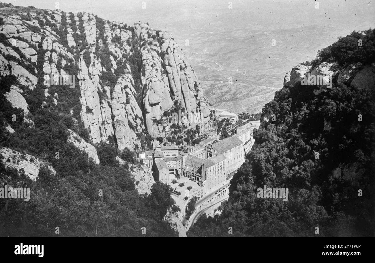 IL MONASTERO SULLA MONTAGNA SACRA È il PIÙ GRANDE SANTUARIO DELLA SPAGNA. Spettacoli fotografici: Il monastero sovrastato da mura torreggianti su Monserrat. 30 km circa da Barcellona si trova il monastero benedettino di Montserrat. Il monastero risale al IX secolo e la sua fondazione è associata alla celebrata Vergine Nera (la Morenata) nella chiesa del monastero. 1946 Foto Stock