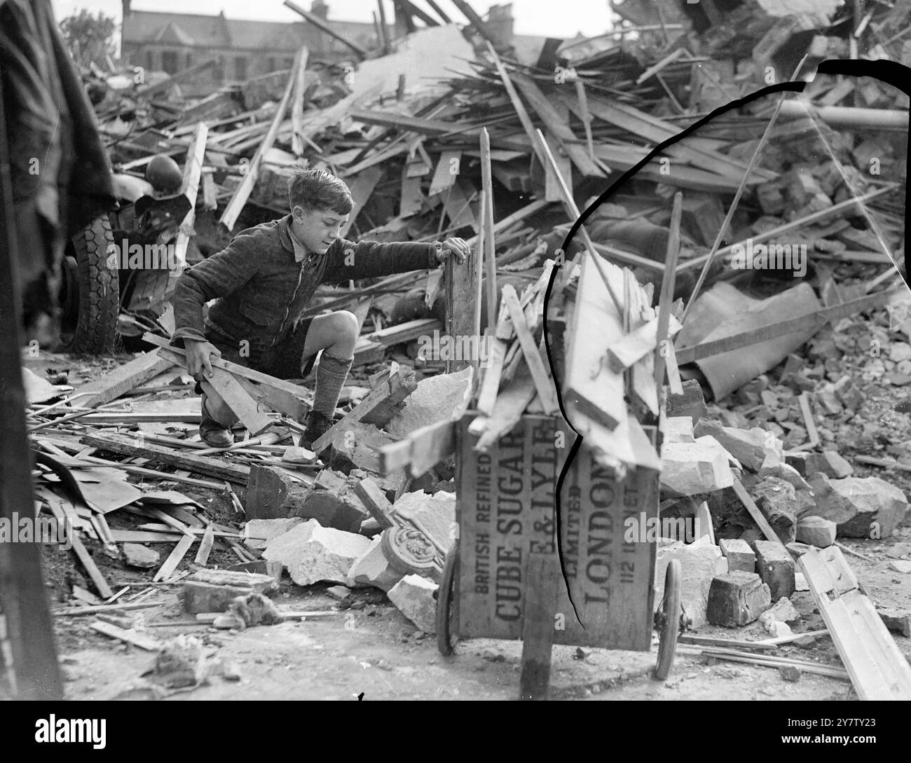IL RAGAZZO DI 11 ANNI LAMBETH VENDE LEGNA DA ARDERE DA CASE BOMBARDATE PER LA SETTIMANA DELLE ARMI DA GUERRA DI LONDRA. Ho già mandato una sterlina e dieci scellini come regalo al suo sindaco. Ronald Spanner, 11 anni di vita presbiteriana, ragazzo di Lambeth, passa il suo tempo libero a raccogliere fondi per la settimana delle armi di guerra di londra e per qualsiasi altra buona causa. Ronald, il cui padre è un vetraio e che ha due fratelli nell'esercito, ha avuto l'idea di raccogliere legna da case bombardate, tagliarla e venderla come legna da ardere ai suoi vicini a due passi per raccogliere fondi. Il suo amico, Dennis Emms, dodicenne, doveva aiutarlo, ma... cavolo Foto Stock