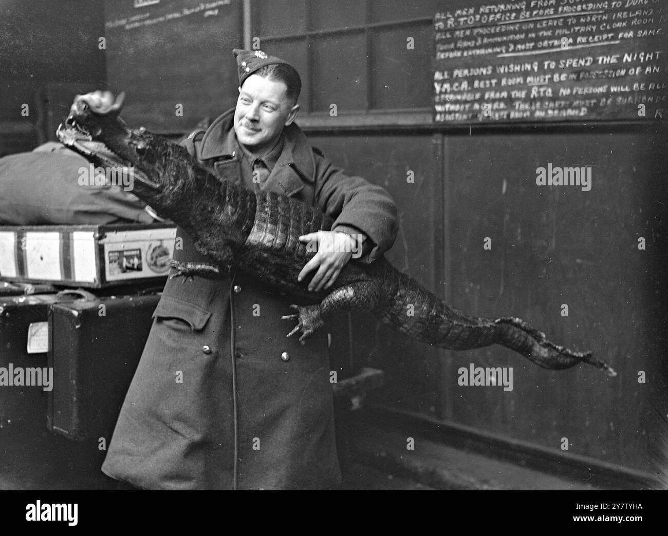 La foto PET di un SOLDATO mostra: Un soldato accarezza dolcemente la schiena di un temibile coccodrillo sulla piattaforma di una stazione di Londra. Il soldato non sembra turbato dalla feroce reputazione di questo rettile crudele e spietato, ma forse è consapevole del fatto che è farcito e non farà mai più del male a nessuno. 8 gennaio 1941 Foto Stock