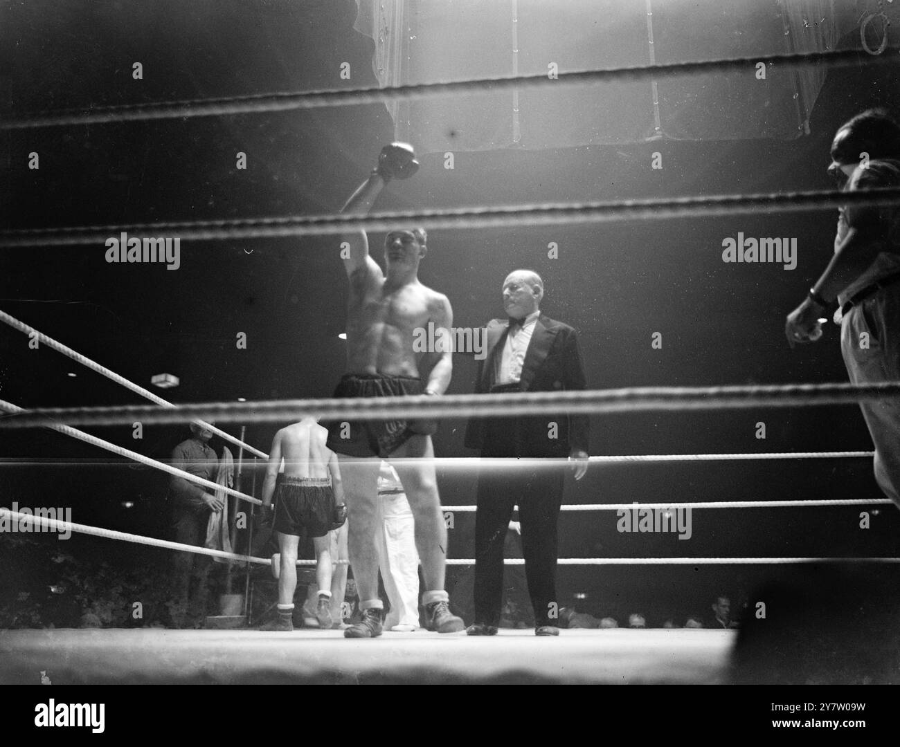 WOODCOCK BATTE MILLS A PUNTI A HARRINGAY Bruce Woodcock, il campione britannico dei pesi massimi, sconfisse Freddie Mills, detentore del titolo cruiserweight, a punti, in una gara di dodici round all'Harringay Arena di Londra. Spettacoli fotografici: Moss Doyong, l'arbitro, tiene la mano di Woodcock, dichiarandolo vincitore, alla fine della lotta. 4 giugno 1946 Foto Stock