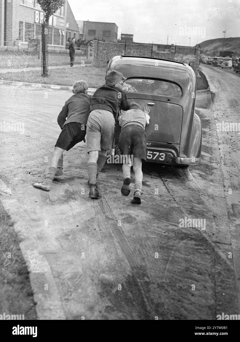 IL FIUME TRABOCCA DOPO LA TEMPESTA - LE AUTO SALVATE dopo la terribile tempesta che il fiume Brent ha traboccato, causando un'inondazione sulla Circular Road nord, dove l'aquaduct che trasportava il Regent's Canal passa sopra la strada. Le auto erano impotenti e venivano trainate e spinte fuori dall'acqua. Spettacoli fotografici: Bambini che spingono un'auto in stallo sulla terraferma dopo aver tentato di viaggiare attraverso l'acqua alluvionale sulla North Circular Road. 27 luglio 1946 Foto Stock