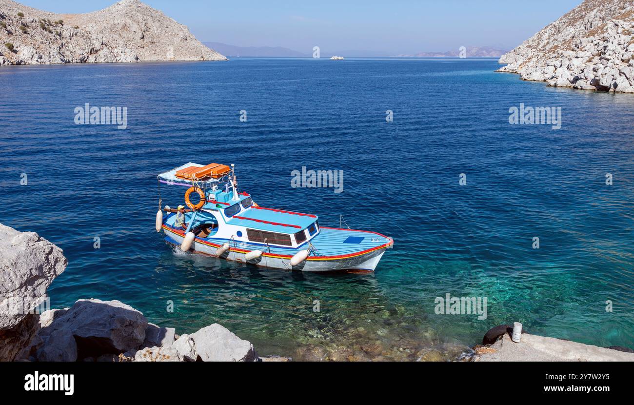 Barca nella baia di San Giorgio nelle isole greche di Simi in Grecia Foto Stock