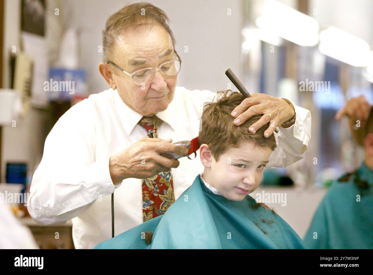 PALO ALTO, CALIF.,--Roy Ruiz lavora per dare a Ben Leonard, 6 anni, di Redwood City, un taglio di capelli mentre cerca di rimanere sveglio sabato 17 gennaio 2004. Il padre di Ben Trask si fa tagliare i capelli con Roy dal 1985 da quando era uno studente di Stanford. Il President Barber Shop che da allora si trova su University Avenue dalla fine degli anni '1920 Foto Stock