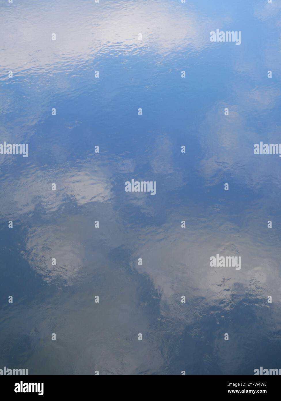 La superficie dell'acqua calma con il riflesso del cielo nuvoloso fornisce una texture rilassante, perfetta come sfondo per vari progetti creativi. Foto Stock