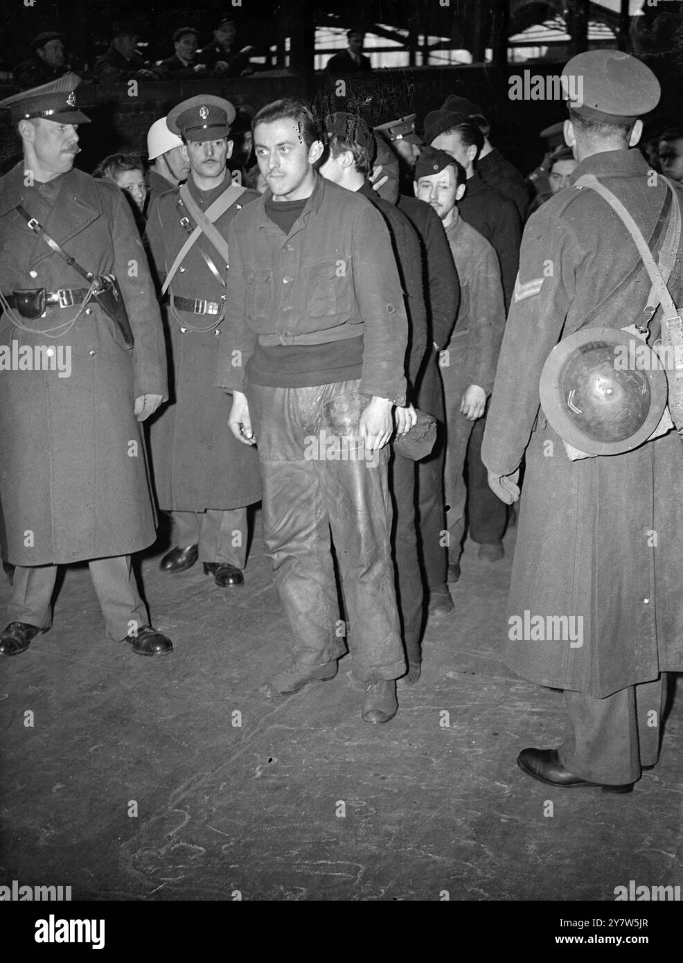 I PRIGIONIERI DI U-BOAT PASSANO ATTRAVERSO le foto di LONDRA: Prigionieri di U-boat sorvegliati dalla polizia militare sulla piattaforma di una stazione di Londra, durante il loro viaggio verso un campo di prigionia di guerra. 16 marzo 1944 Foto Stock