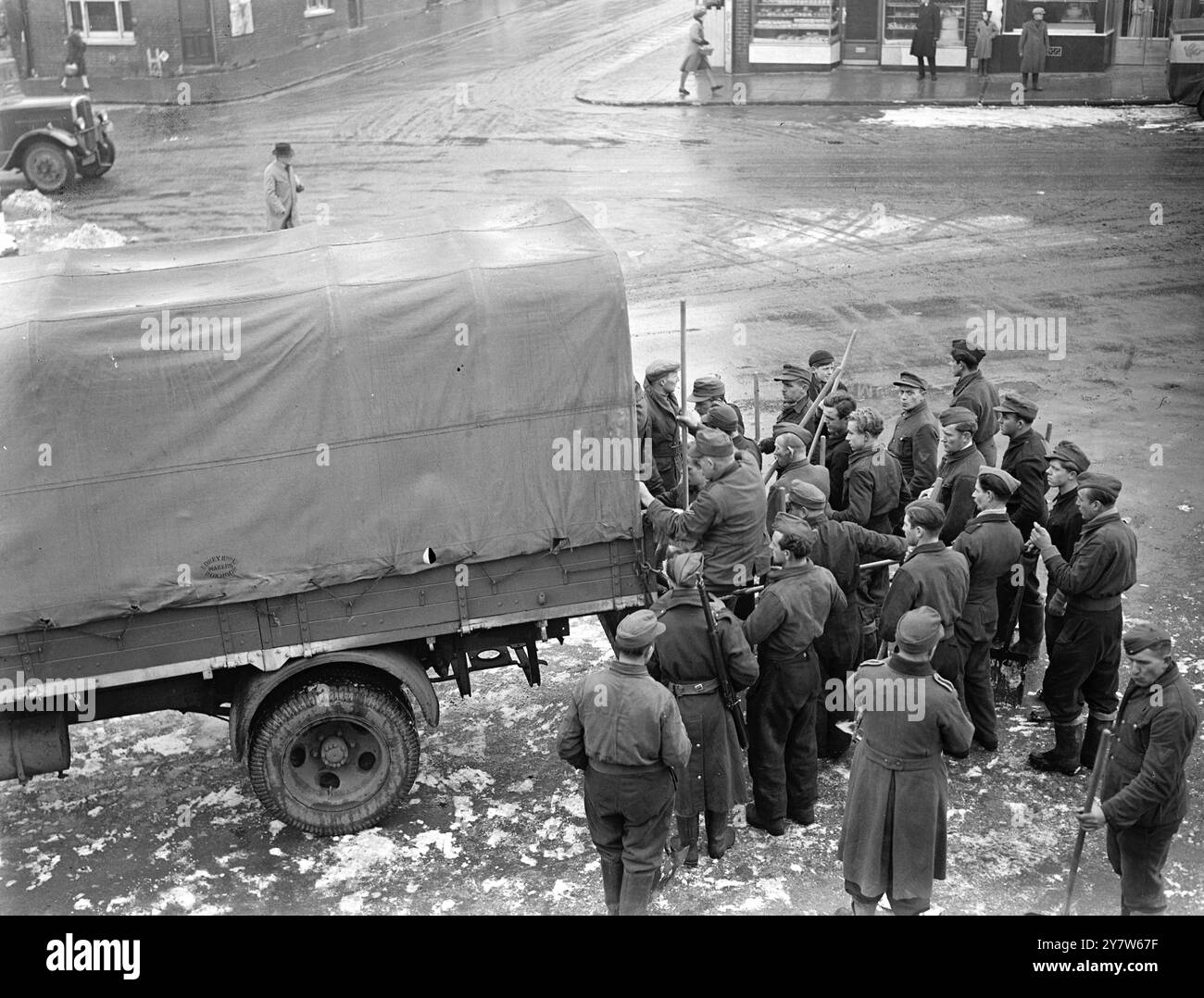 I PRIGIONIERI DI GUERRA TEDESCHI LIBERANO LA NEVE DALLE STRADE DELL'INGHILTERRA MERIDIONALE. Gruppi di prigionieri di guerra tedeschi stanno ripulendo la neve dalle strade dell'Inghilterra meridionale. Lavorano sotto la guardia armata, e mangiano nei depositi del Consiglio locale tornando al campo alla fine dei giorni di lavoro. Spettacoli fotografici: A metà giornata un gruppo di lavoro tedesco prigioniero di guerra salpa su un camion che li porta al locale deposito del Consiglio per il pranzo. 27 gennaio 1945 Foto Stock