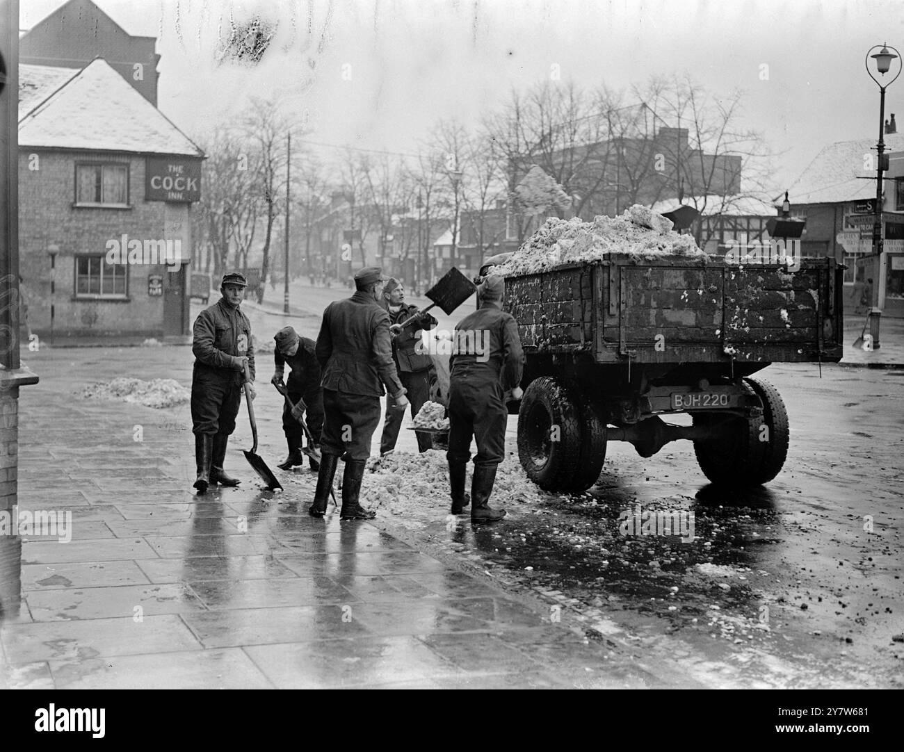 I PRIGIONIERI DI GUERRA TEDESCHI LIBERANO LA NEVE DALLE STRADE DELL'INGHILTERRA MERIDIONALE. Gruppi di prigionieri di guerra tedeschi stanno ripulendo la neve dalle strade dell'Inghilterra meridionale. Lavorano sotto la guardia armata, e mangiano nei depositi del Consiglio locale tornando al campo alla fine dei giorni di lavoro. Foto: Un prigioniero di guerra tedesco, una festa di sgombero della neve al lavoro nel sud dell'Inghilterra. 27 gennaio 1945 Foto Stock