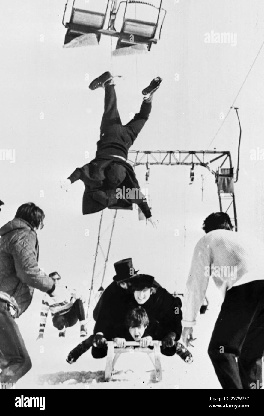 RINGO'S PREDICAMENTObertauern, Austria: In questa scena alpina per il loro nuovo film, Help! , Tre Beatles (dal basso): Paul McCartney, John Lennon e George Harrison) giacciono su uno slittino, mentre il collega Beatle Ringo Starr viene portato in aria da uno skilift, durante le riprese di location qui oggi. Solo pochi giorni fa, il gruppo musicale popolare stava facendo scene per il loro secondo film nelle soleggiate Bahamas. Questo pomeriggio, una valanga ha tuffato giù per le piste vicino a dove i Beatles avevano precedentemente fatto le scene per il loro nuovo film. 15 marzo 1965 Foto Stock