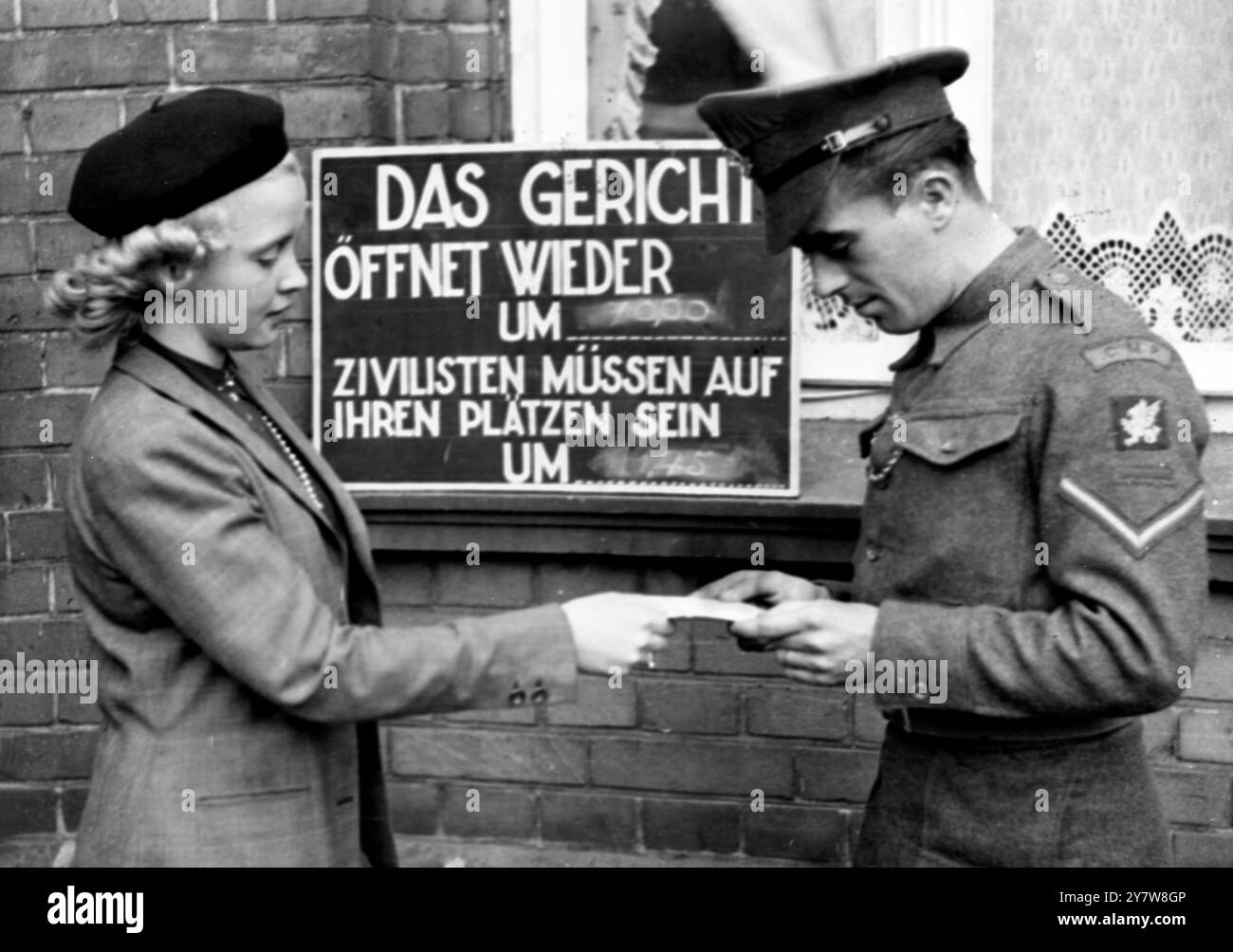 Controlli di sicurezza a Belsen TrialLuneberg , Germania : il caporale T. Webb di Willesden , Londra , controlla il lasciapassare di un civile non identificato al di fuori dell' aula di tribunale mentre continua il primo dei grandi processi penali di guerra . 19 settembre 1945 Foto Stock