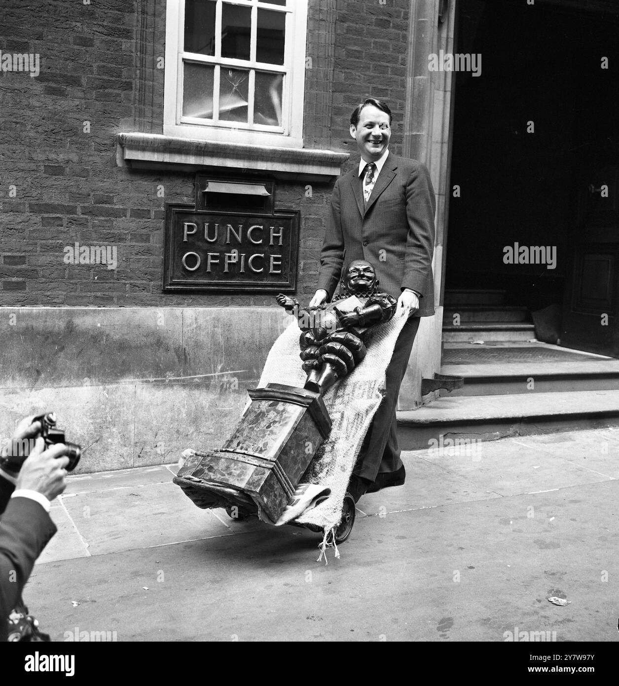 Un cambio d'ufficio per la figura di bronzo di Mr Punch che si trova all'ingresso di 10 Bouverie Street, Londra da molti anni. Oggi William Davis, editore della popolare rivista, usò una carriola per portare Mr Punch nei suoi nuovi uffici a Tudor Street. Punch occupa il sito al numero 10 di Bouverie dal 1843. Il signor Davis ha assunto la sua nomina il primo gennaio di quest'anno.21 luglio 1969 Foto Stock