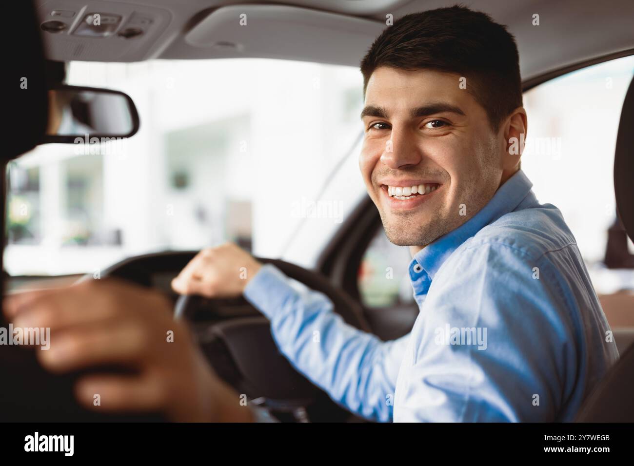 Happy Young Man seduto in auto nel Dealership Center Foto Stock