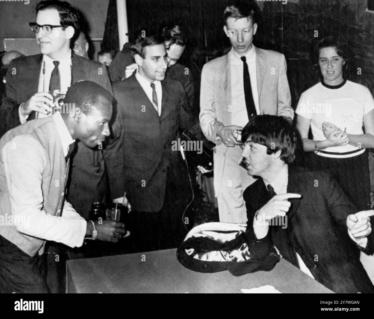 Paul McCartney con un cameriere che serve rinfreschi durante una conferenza stampa dopo l'arrivo dei Beatles a Nassau, Bahamas, 23 febbraio 1965 Foto Stock