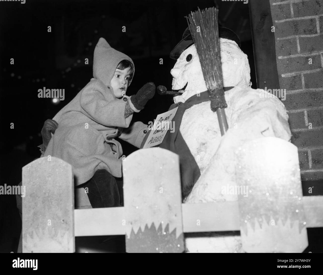 Barry Yowdell, di tre anni, di Abingdon, Berkshire, è arrivato alla stazione di Paddington per trascorrere il Natale a Londra e si è trovato faccia a faccia con un pupazzo di neve. Fa parte di un modello su larga scala presso la stazione il 22 dicembre 1956 Foto Stock