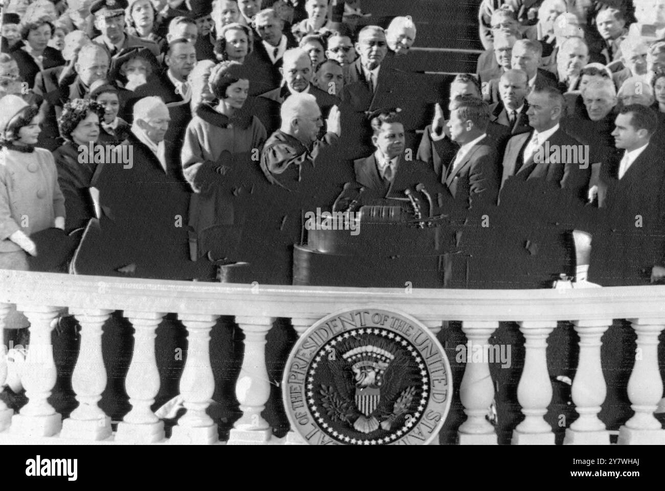 La scena nel ruolo di John F Kennedy è giurata come 35° presidente americano dal giudice della Corte Suprema Earl Warren (centro sinistro). Tra di loro c'è l'impiegato di corte James R Brown. A sinistra della foto (da sinistra a destra) ci sono la signora Jacqueline Kennedy, la signora Mamie Eisenhower e il presidente uscente Dwight Eisenhower. All'estrema destra ci sono i due vicepresidenti, Lyndon B Johnson (accanto a Kennedy) e Richard Nixon . Sfondo a sinistra (alto in uniforme) è il figlio del presidente uscente, il maggiore John Eisenhower. 20 gennaio 1961 Foto Stock