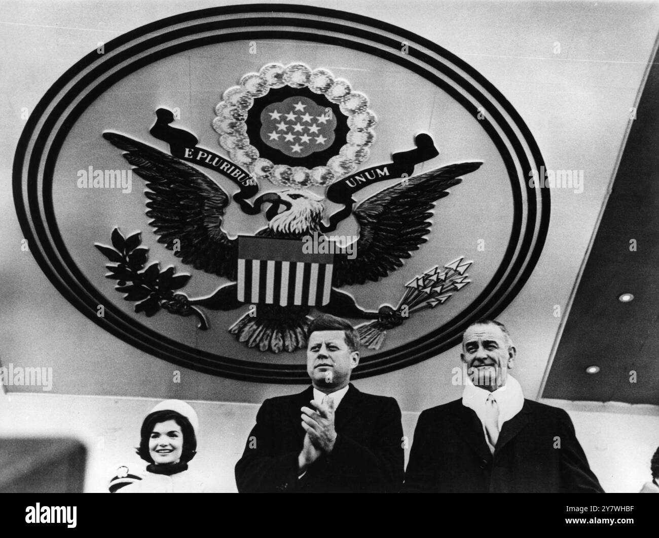 Sotto il sigillo degli Stati Uniti , il Presidente John F Kennedy plaude ad uno dei carri della Inauguration Parade di Washington del 20 gennaio 1961 . Sulla sinistra si trova Jacqueline , la moglie del Presidente , e sulla destra c'è il Vice Presidente Lyndon B Johnson Foto Stock