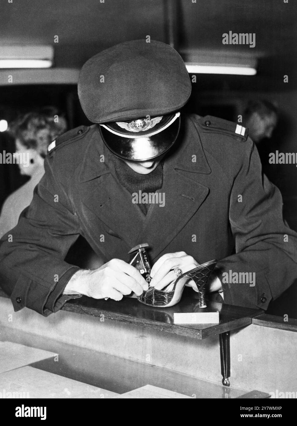 Copenaghen , Danimarca - Anita Ekberg si è rotta una scarpa mentre era in transito all'aeroporto di Kastrup con il marito - visto qui un funzionario SAS che muta la sua scarpa con nastro adesivo e un graffatore - 25 novembre 1957 Foto Stock