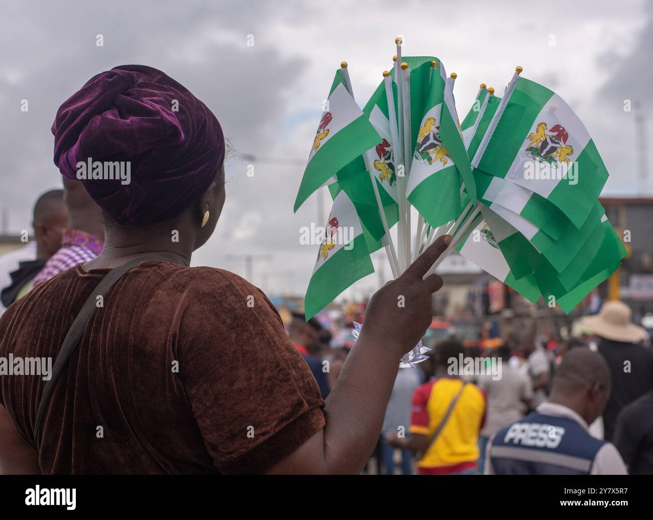 Una donna tiene fuori le bandiere Nigeria in vendita a Lagos martedì 1 ottobre 2024. I nigeriani sono fuori in occasione dell'Independence Day per protestare contro il cattivo governo e il saluto Foto Stock