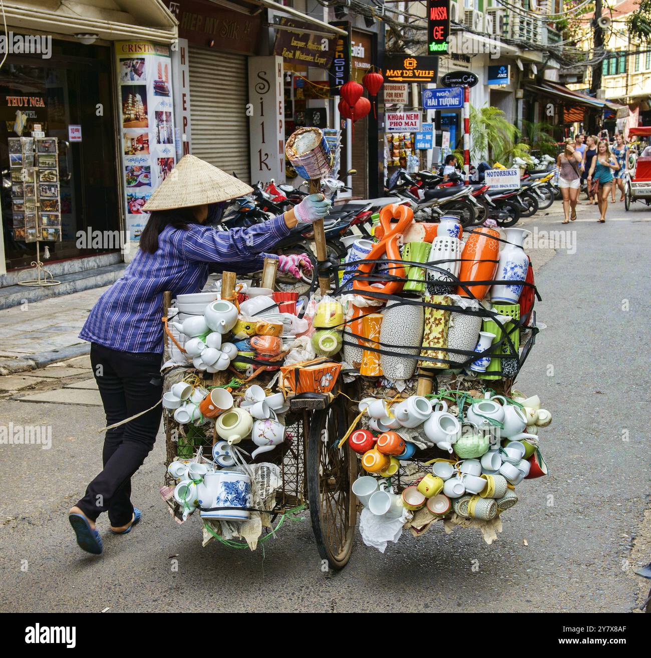 Fornitore spinge il suo carico attraverso le strade di Hanoi, Vietnam. Foto Stock