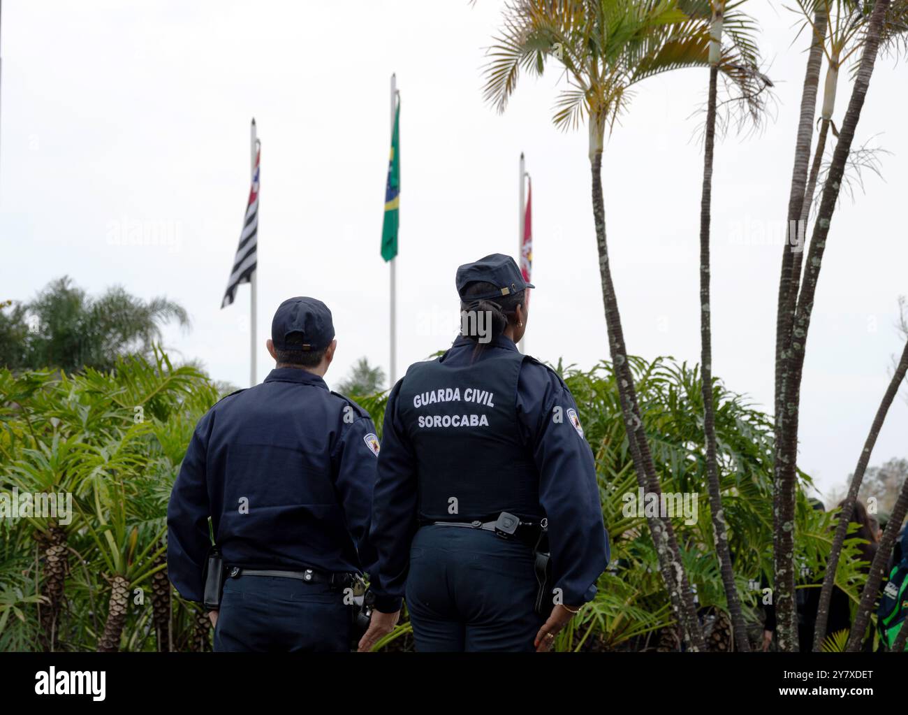Due agenti di polizia con le spalle alla fotografia e con le bandiere sollevate durante un evento civico nella città di Sorocaba, São Paolo, Brasile. Foto Stock