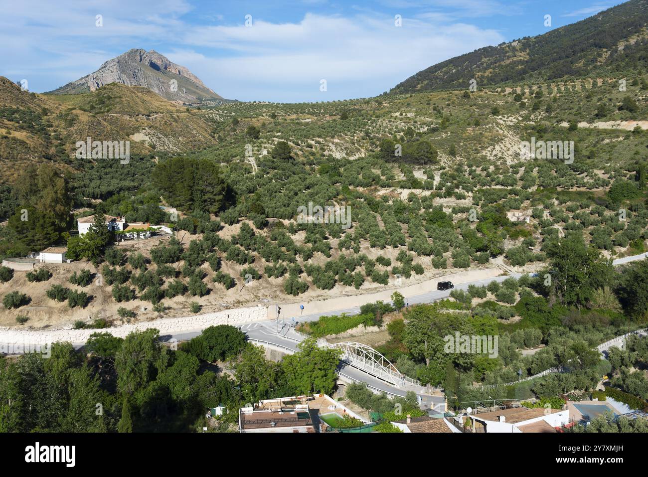 Verdi colline e un villaggio su una strada tortuosa, circondato da lussureggianti paesaggi naturali, vicino a Bedmar y Garciez, Bedmar y Garciez e al Parco naturale della Sierra Magina Foto Stock