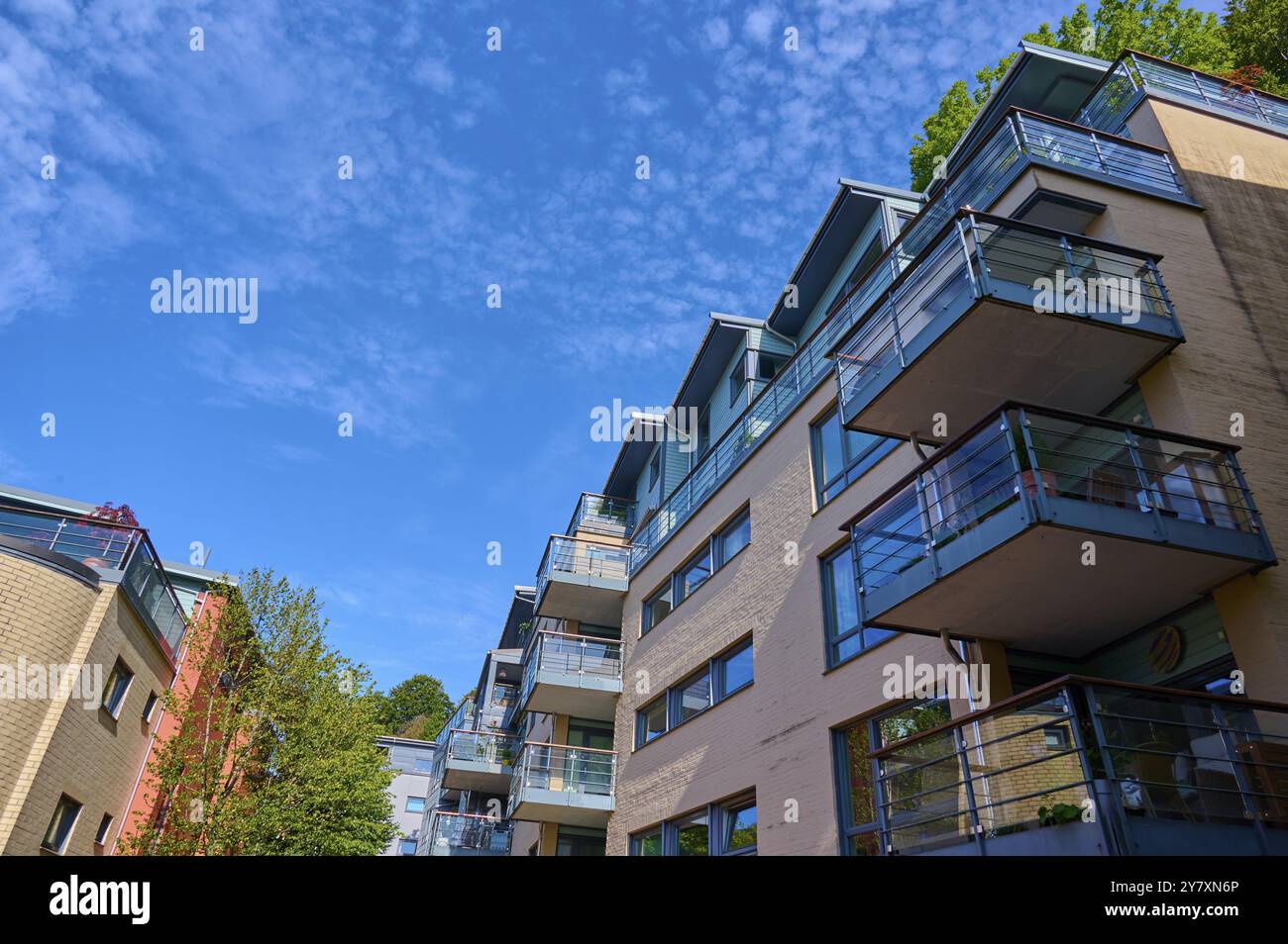 Moderno edificio residenziale con diversi balconi e ringhiere di vetro sotto un cielo blu con nuvole in un paesaggio urbano, Bergen, Vestland, Norvegia, Europa Foto Stock