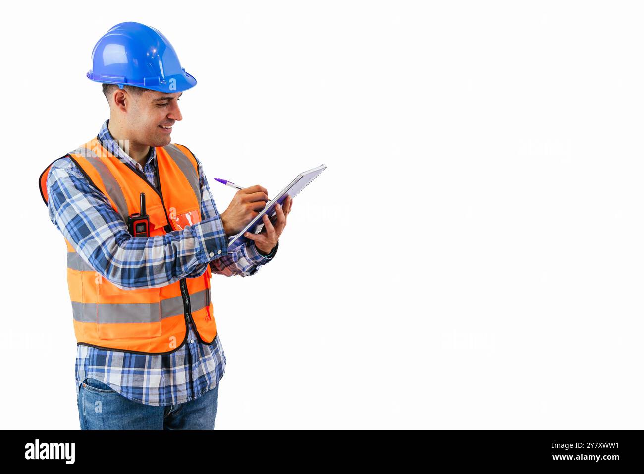un ingegnere copyspace che indossa un giubbotto di sicurezza arancione riflettente e un elmetto scrive le note di progetto con una penna in un notebook in un cantiere edile. emp Foto Stock