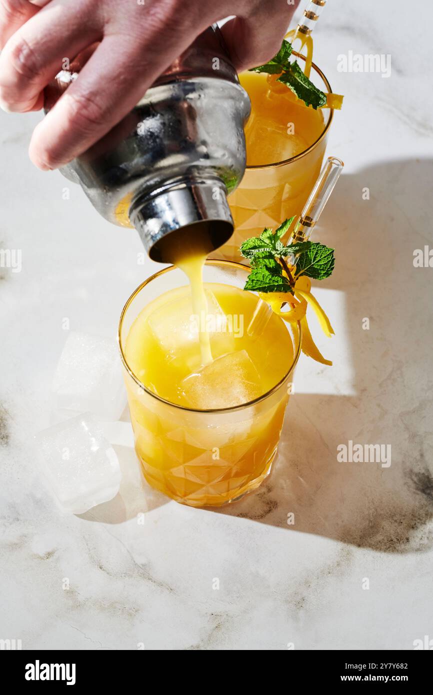 Cocktail di frutta della passione e tequila con scorza di limone e menta Foto Stock