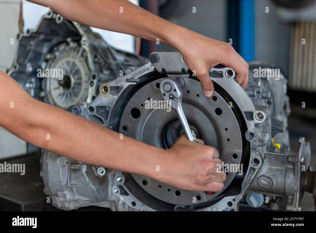 Primo piano di un adolescente che ripara un cambio di un'auto usata in un'officina di riparazione auto. Riparazione e manutenzione di automobili. Foto Stock