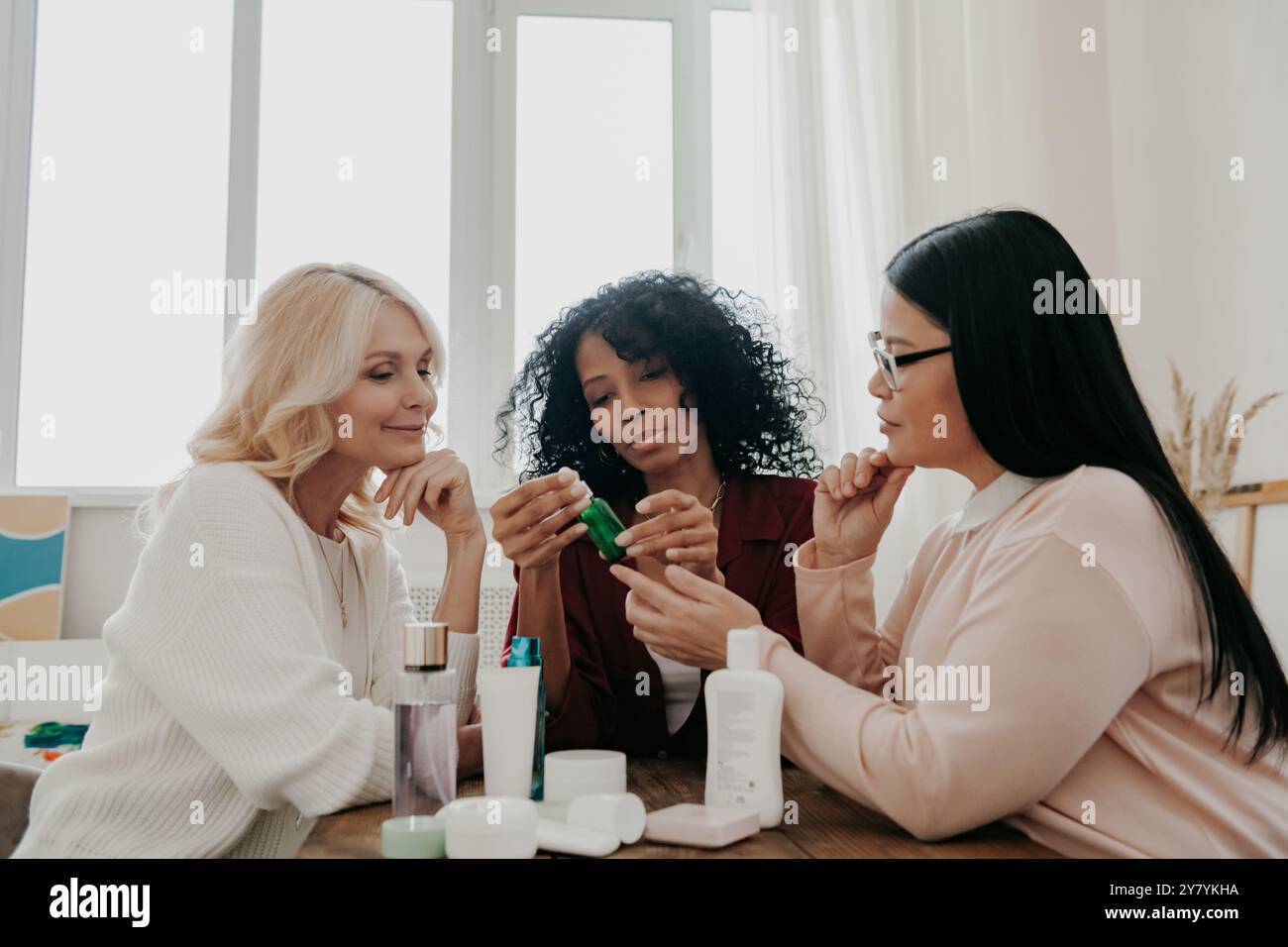 Tre donne mature che esaminano trattamenti di bellezza sedute alla scrivania insieme Foto Stock