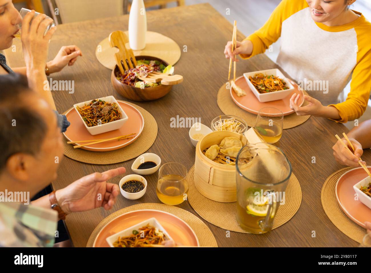 A casa, si mangia cucina asiatica, la famiglia asiatica si gusta un pasto insieme a bacchette al tavolo da pranzo Foto Stock