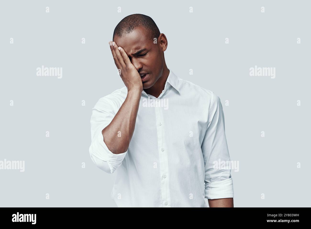Così stanco. Giovane africano che fa un volto mentre si trova su uno sfondo grigio Foto Stock Così stanco. Giovane africano che fa un volto mentre si trova su uno sfondo grigio Foto Stock
