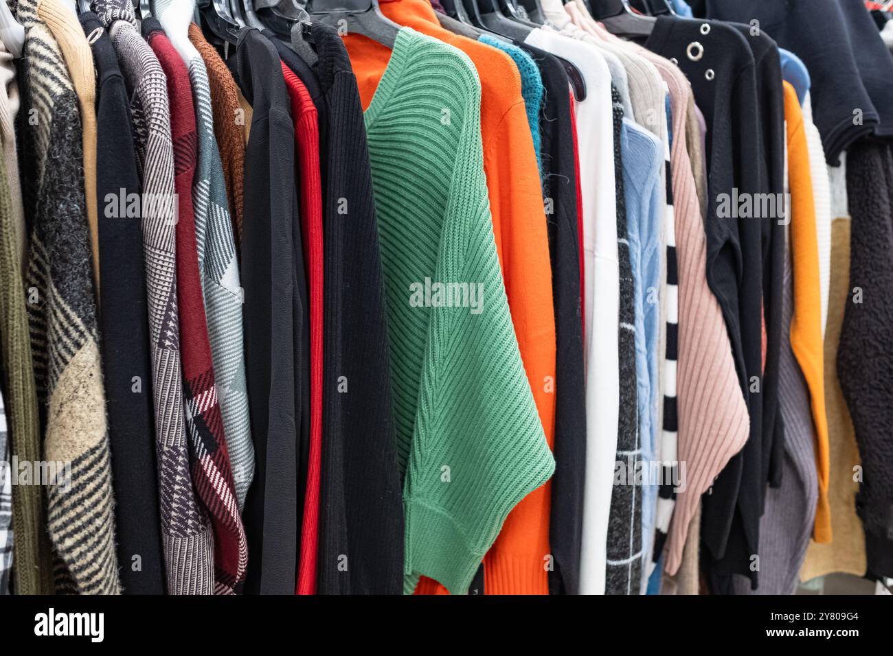 Abbigliamento donna - collezione autunno inverno. Abbigliamento in maglia alla moda, appeso su rack per l'esposizione. Pullover casual da donna, stagione di saldi. W multicolore Foto Stock